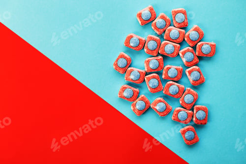 Preview: capsules for kitchen dishwashers on a blue and red background. flat lay