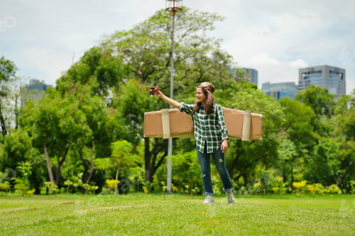 Preview: Portrait of red hair kid in pilot costume holding wooden plane running in summer field