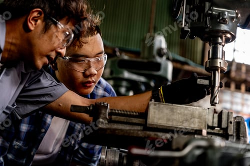 Preview: Asian worker in production plant drilling at machine.