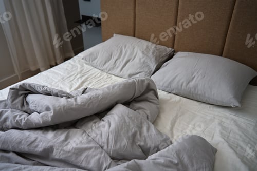 Preview: Crumpled bed with pillows, blanket and crumpled sheets in bedroom