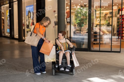 Preview: Woman showing shopping bags to friend in wheelchair at mall
