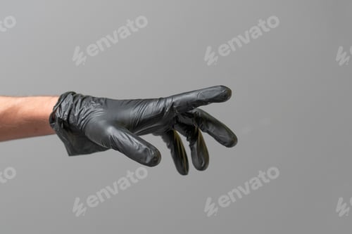 Preview: Hand with Black Glove Reaching Out on Grey