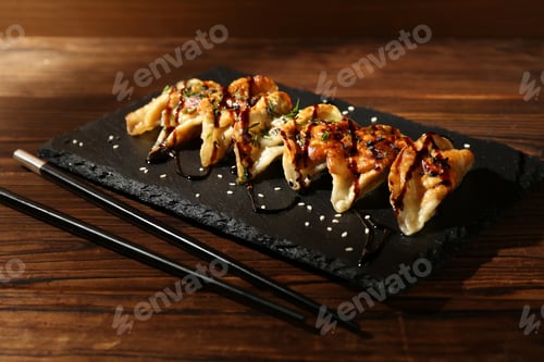 Preview: Tasty fried gyoza (dumplings) and chopsticks on wooden table, closeup