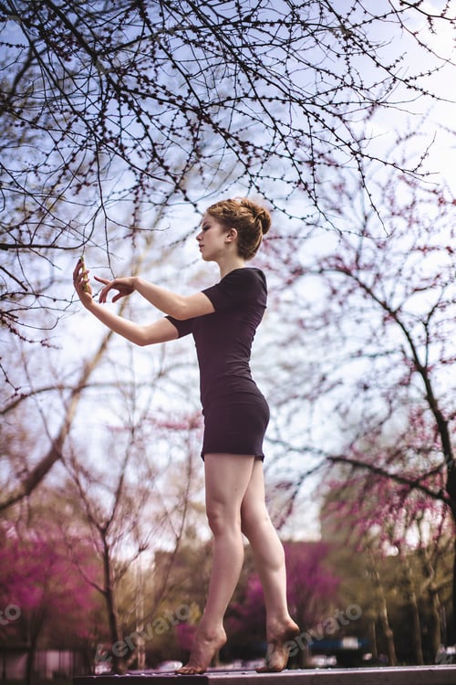 Preview: Modern dancer striking a pose and using a smart phone in a urban park