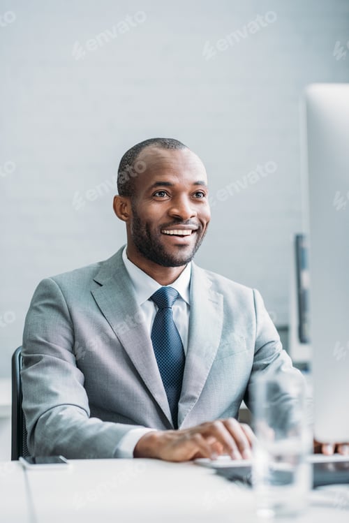 Smiling Man Wearing Suit at Office Desk