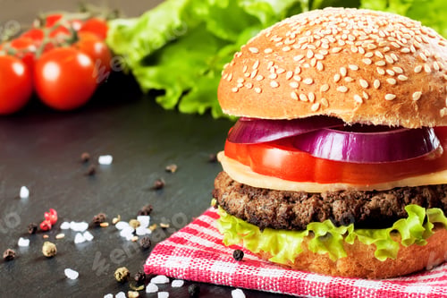 Preview: Homemade cheeseburger on black slate surface.