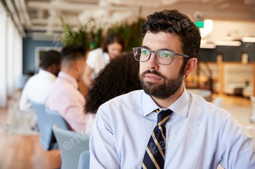 Preview: Businessman In Modern Office With Colleagues Meeting Around Table In Background