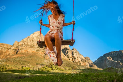 Preview: Beautiful healthy woman on a swing smiling in front of Table Mountain, Cape Town.