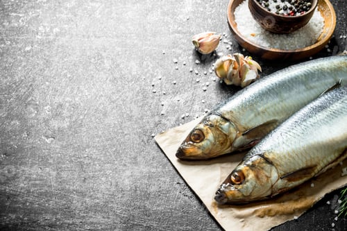 Preview: Salted herring on paper with garlic and spices.