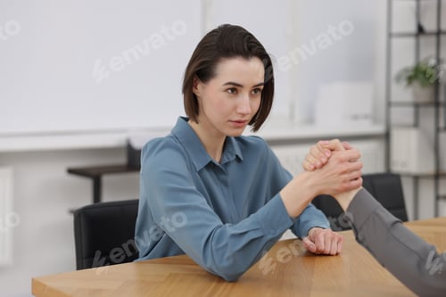 Preview: Competition concept. Businesswomen arm wrestling at table in office, closeup