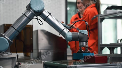 Preview: A robot is working on a project with a person in an orange shirt