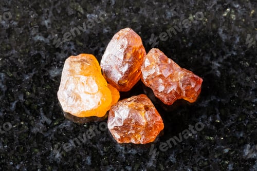 Preview: few raw hessonite grossular crystals on black