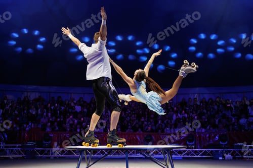 Preview: Young pair of acrobats, man and woman, on roller skates perform in a circus on a small round stage.