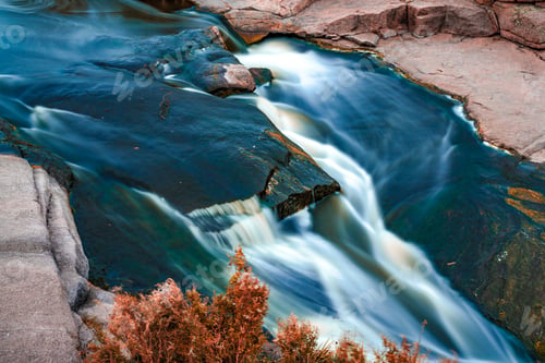 Preview: Stream runs among white wet stones covered with grass in golden autumn