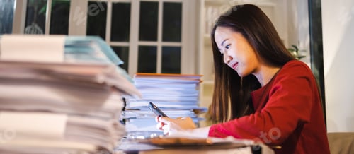 Preview: Happy Asian woman using smartphone during overtime at home office. Busy people working.