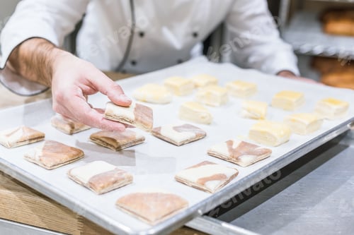 Preview: Cropped view of baker hands with uncooked dough on tray