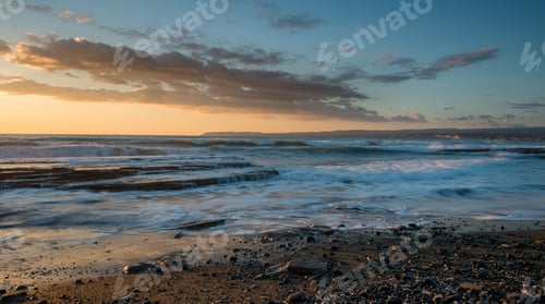 Preview: Dramatic beautiful sunset on a rocky coast. Waves breaking on the rocks.