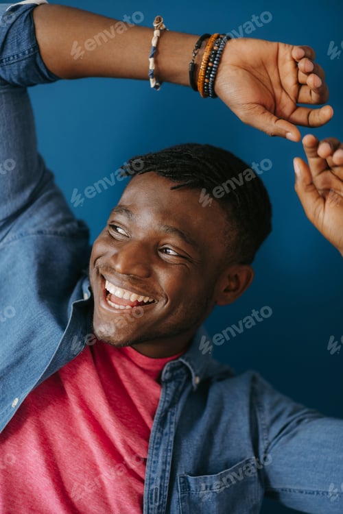 Preview: Handsome young African man in casual wear smiling and gesturing on blue background