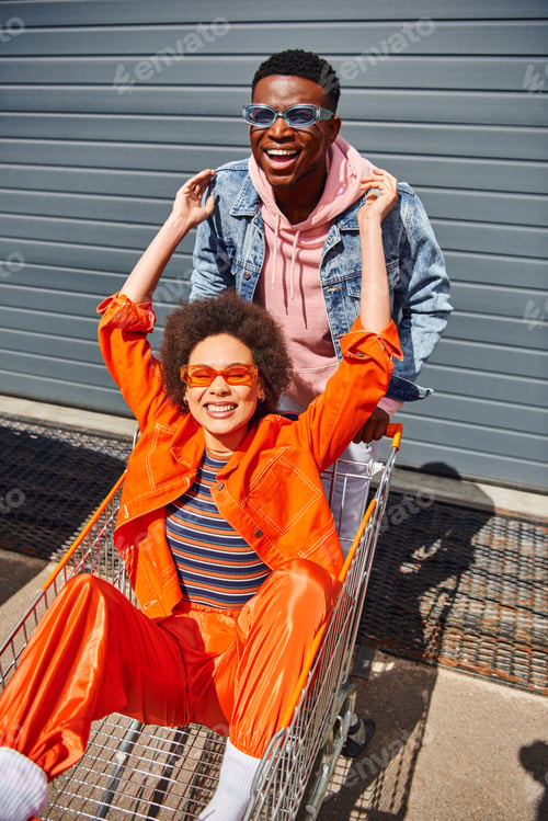 Preview: Positive and fashionable african american best friends in sunglasses and bright clothes looking