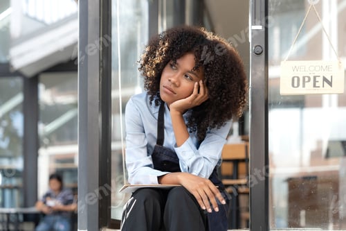 Preview: black woman waiter of street cafe is waiting for clients, customersm she is bored, no people in