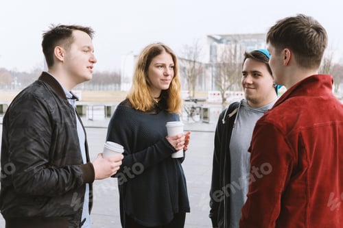 Preview: group of teenage friends having a conversation while standing together on city street