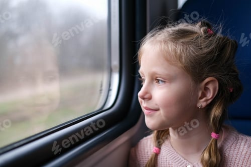 Preview: The child is on the train and looks out the window. A little girl travels in a train.