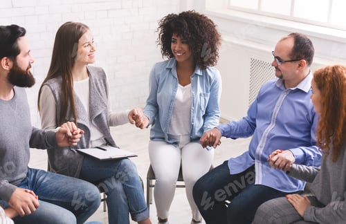Preview: Young multi-cultural group of people holding hands during therapy session