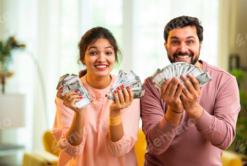Preview: Happy Indian couple holding and showing rupee notes, symbolizing unexpected financial success