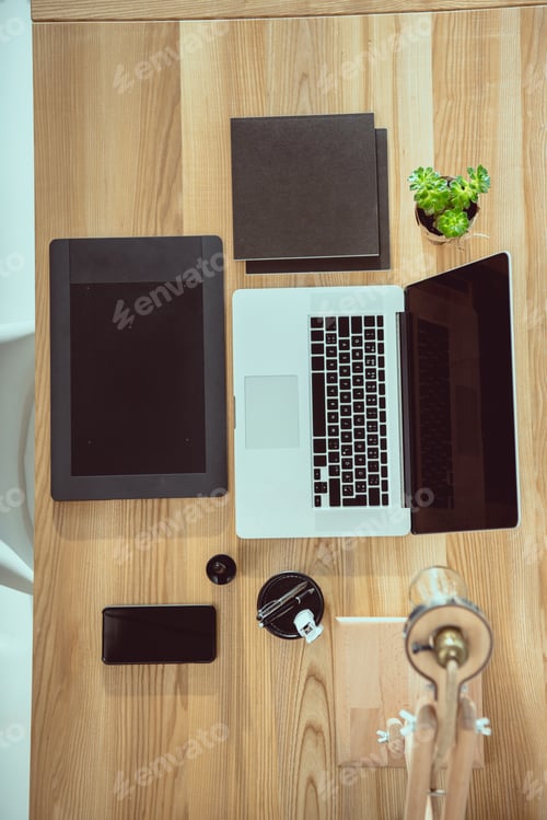 Preview: top view of laptop with graphics tablet and smartphone on wooden tabletop at office