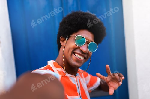 Preview: Happy, smiling young African American man taking selfie in coastal Mediterranean village.