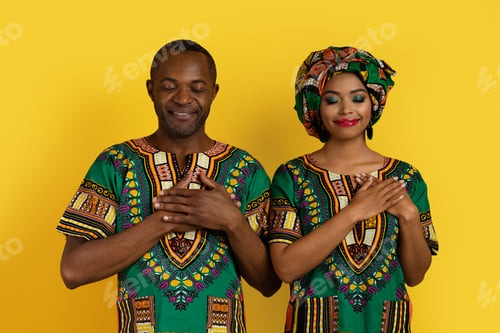 Preview: Peaceful african lovers in traditional costumes holding hands on chest