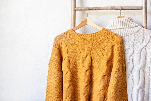 Preview: Warm autumn sweaters on hangers. Comfort knitwear for cold days