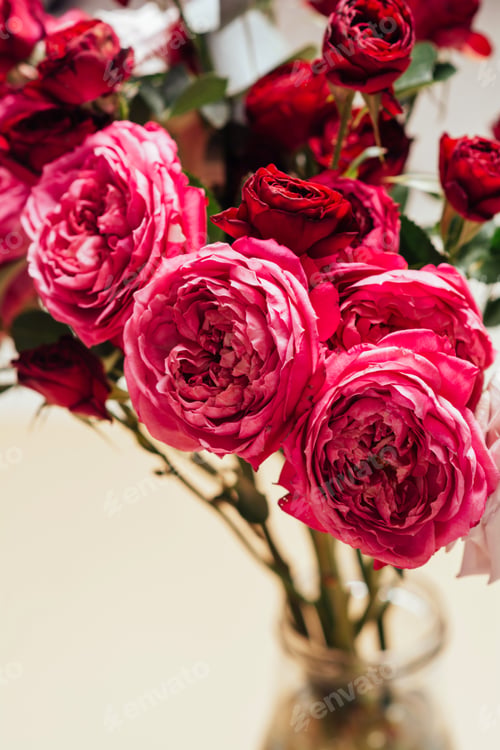 Preview: Bouquet of beautiful flowers in a transparent glass bottle on a beige background.