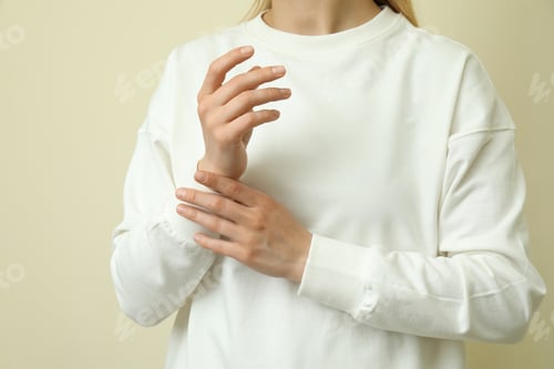Preview: Young woman in white sweatshirt against beige background