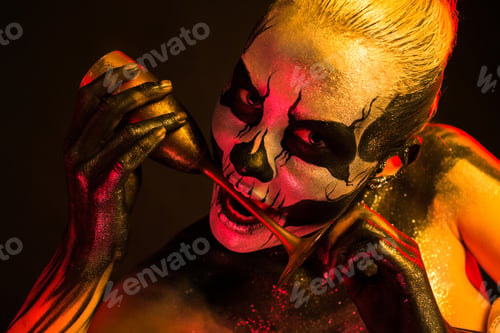 Preview: Pretty girl with skeleton makeup holds glass