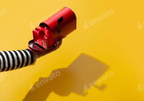 Preview: Female hand hold gfit box in mailbox on yellow background