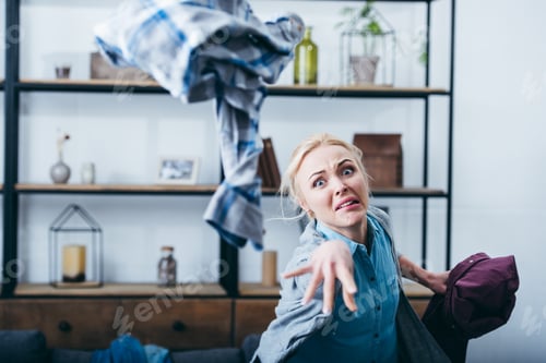Preview: aggressive woman throwing clothes in living room after breaking up with boyfriend