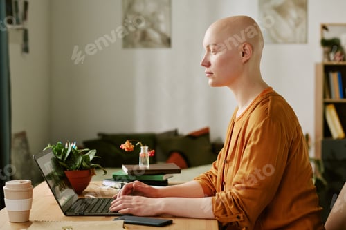 Preview: Young Adult Woman with Alopecia Using Laptop While Working Indoors