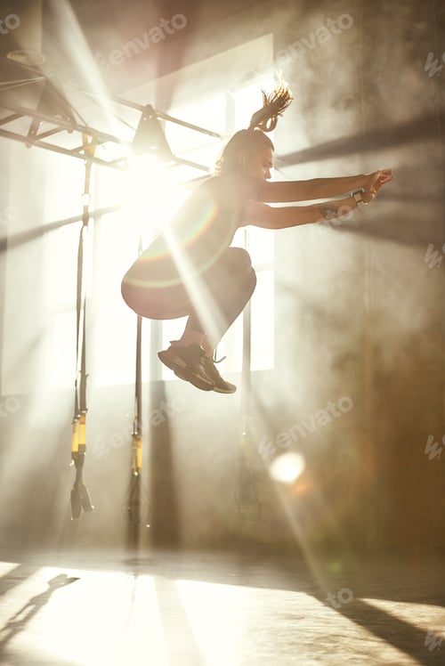 Preview: Higher and higher. Side view of young athletic woman in sport clothing jumping while exercising in