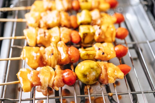 Preview: BBQ grill with a variety of meats, complete with tomatoes and bell peppers.