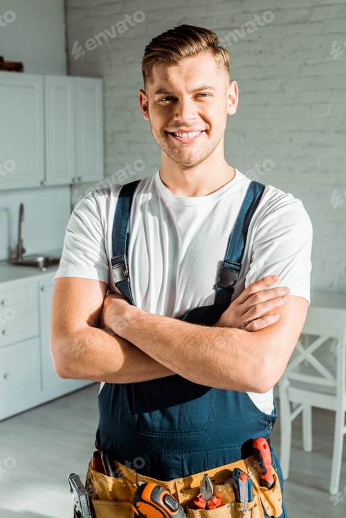 Preview: happy installer in overalls standing with crossed arms