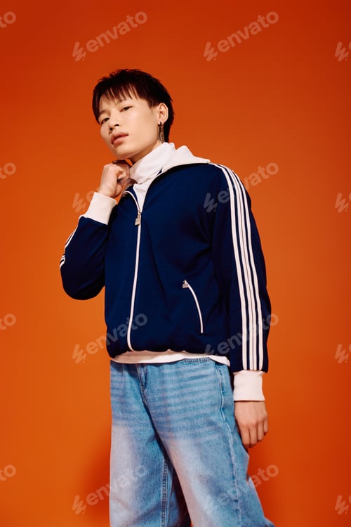 Preview: Stylish young asian man posing confidently against a vibrant orange backdrop