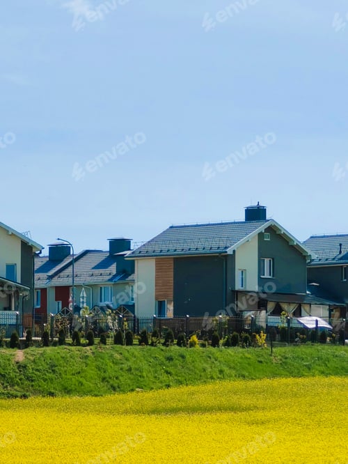Preview: cottage village of small expensive houses on the background of a blooming meadow
