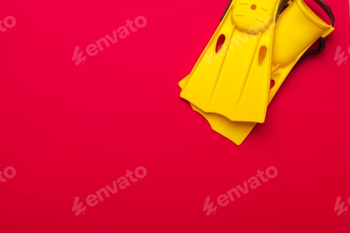 Preview: Bright yellow flippers resting on a vibrant red background for aquatic activities