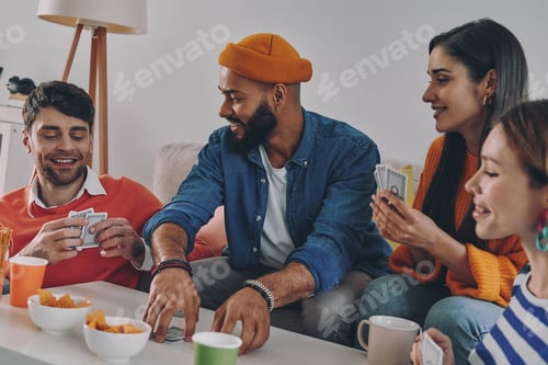 Preview: Beautiful young people playing cards and smiling while enjoying carefree time together