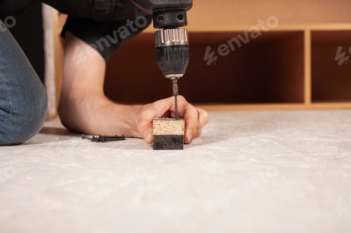 Preview: A man drills a hole in the wood against the background of an inverted closet on the floor