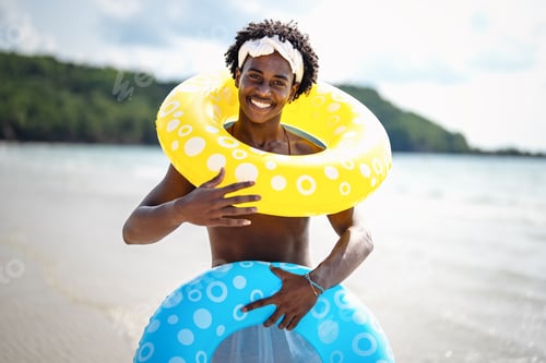 Preview: Smiling young black man enjoys every moment of her tropical escape, playing on the beach