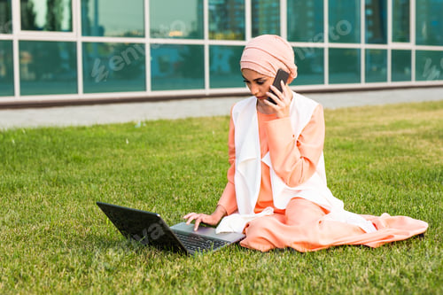 Preview: Young Muslim Woman Using Mobile Phone and Laptop In Park
