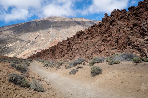 Preview: a small mountain with a dirt path going through it and a rocky cliff in the