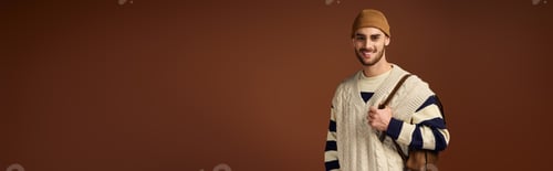 Preview: Young man's stylish winter fashion in trendy beanie on brown studio backdrop